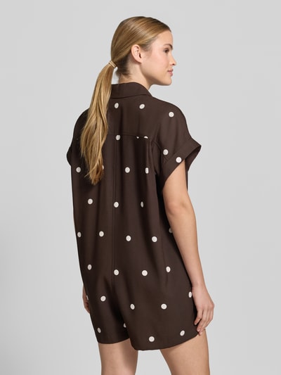 Frauenmodel trägt Lockeren Jumpsuit mit Knopfdetail - curated by Mary Braun von Style Icon Collection, Braun mit weißen Punkten, Relaxed-Fit, Allover-Look, Hemdblusenkragen, Knopfleiste, Ganzkörperansicht Rückansicht, Rückenlänge bei Größe S 65 cm, Brustweite 60 cm, Ärmellänge 14 cm, Gesamtlänge 84 cm, Innenbeinlänge 5 cm.