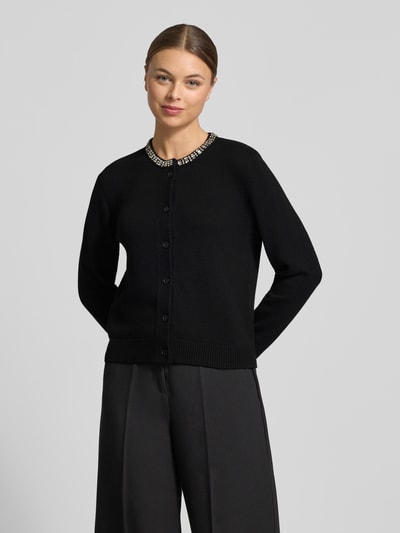 Vrouwenmodel draagt Regular Fit Cardigan met viscose-kasjmiermix model 'Kosta' van JOOP!, materiaalmix, met siersteentjes, tricotlook, knoopsluiting, elastische boorden; ruglengte maat 36: 56 cm, mouwlengte maat 36: 66 cm. Vooraanzicht heuphoogte.