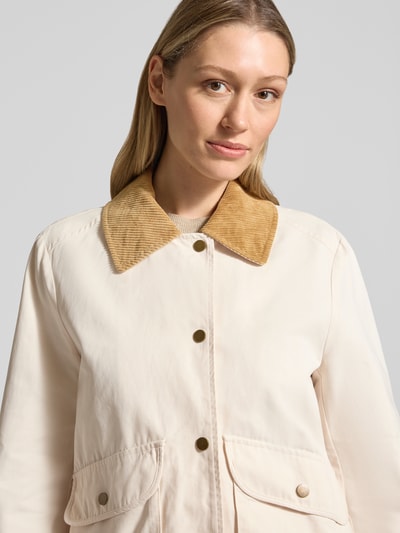 Vrouwenmodel draagt Jacke mit Umlegekragen und aufgesetzten Pattentaschen van WHITE LABEL in crème met bruine platte kraag en drukknoopsluiting, recht model, opgestikte klepzakken, ruglengte maat 36: 67 cm, schouderbreedte: 44 cm, borstwijdte: 53 cm, mouwlengte: 63 cm, vooraanzicht bovenlichaam