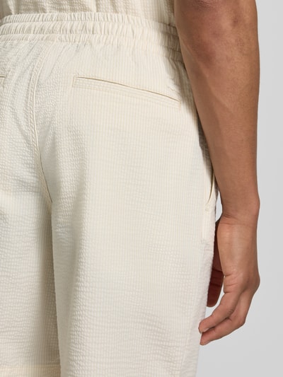 Männermodel trägt Loose Fit Shorts aus Baumwoll-Mix von Lacoste in weiß mit feiner Seersucker-Struktur, Nahaufnahme Rückansicht. Optik:Allover-Muster, Passform: Regular-Fit, Muster: Gestreift, Applikation: Label-Stitching, Bundabschluss: elastisch mit Tunnelzug, Taschen: seitliche Eingrifftaschen, Materialverarbeitung: Seersucker, Material: Baumwoll-Mix.