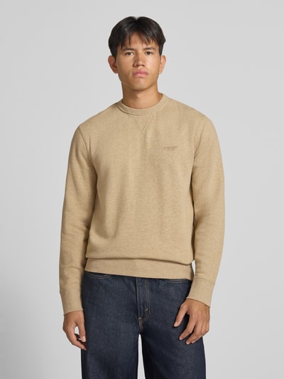 Männermodel trägt Sweatshirt aus Baumwoll-Mix von Superdry in Beige mit Rundhalsausschnitt und Label-Stitching, Ganzkörperansicht von vorne. Rückenlänge bei Größe M: 66 cm, Ärmellänge: 62 cm, lockere Passform, elastische Abschlüsse.