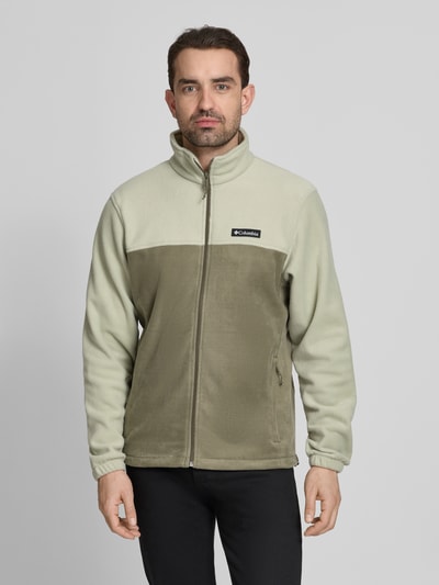 Männermodel trägt zweifarbige Regular Fit Fleecejacke mit Logo-Patch Modell 'Mountain' von COLUMBIA, Stehkragen, Reißverschluss, Eingrifftaschen, elastische Ärmelabschlüsse, Rückenlänge 70 cm, Ärmellänge 68 cm, Ganzkörperansicht von vorne.
