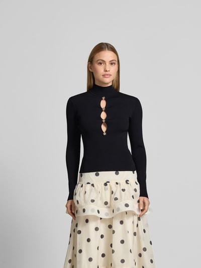 Frauenmodel trägt Slim Fit Longsleeve aus Viskose-Mix von Self-Portrait in Schwarz mit Cut-Outs, Zierbesatz, Rollkragen, Ganzkörperansicht von vorne.
