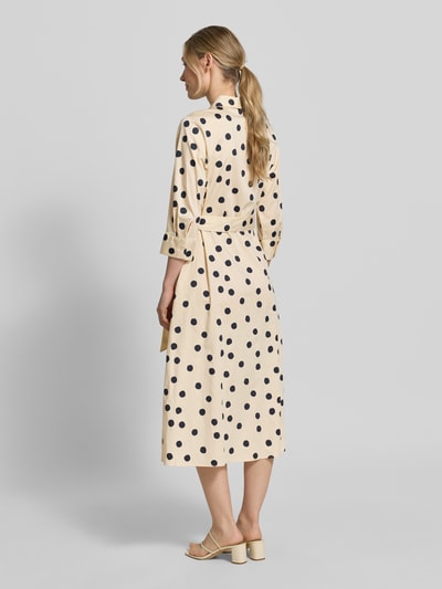 Frauenmodel trägt Regular Fit Blusenkleid aus Baumwoll-Mix von s.Oliver BLACK LABEL, Optik:Allover-Muster mit Polka-Dots, Midi-Länge, seitliche Eingrifftaschen, Taillengürtel, Hemdblusenkragen, Ballonärmel mit Manschette, Farbe beige mit schwarzen Punkten, Ganzkörperansicht Rückansicht.