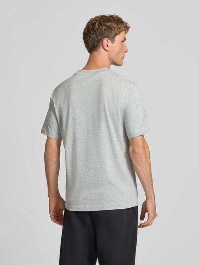 Männermodel trägt grau-meliertes T-Shirt mit Label-Stitching Modell 'ESSENTIALS' von New Balance, gerader Schnitt, Rückenansicht, Ganzkörperansicht Rückansicht.