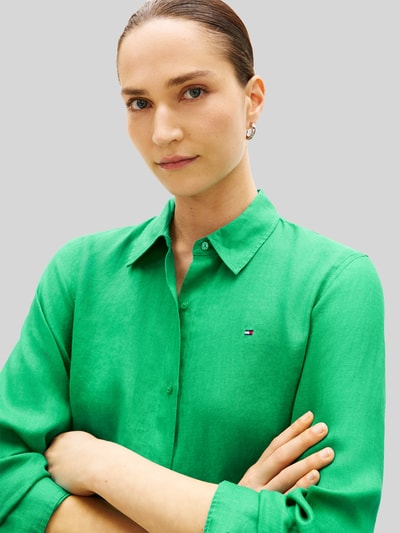 Frauenmodel trägt Relaxed Fit Langarmbluse aus reinem Leinen von Tommy Hilfiger, Optik: Unifarben, Logo-Stitching, Materialverarbeitung: Flammgarn, Passform: Relaxed-Fit, Kragenform: Hemdkragen, Verschluss: Knopfleiste, Ärmelabschluss: Manschette, Nahaufnahme Oberkörper.