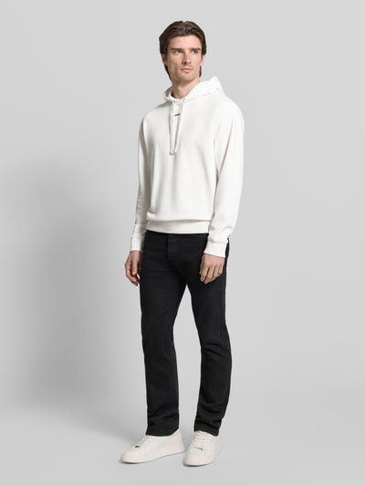 Männermodel trägt Regular Fit Hoodie aus reiner Baumwolle Modell 'DAPO' von HUGO, unifarben, Sweat-Textur, Ganzkörperansicht von vorne.