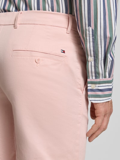 Mężczyzna nosi Regular Fit Bermudas aus Baumwoll-Mix von Tommy Hilfiger w kolorze jasnoróżowym, jednolite, logo-stitching, bawełniany materiał, tylne i boczne kieszenie, szlufki na pasek, guziki i zamek, detalowe ujęcie tylnej części