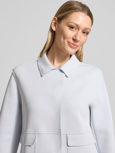 Kobiece model prezentuje żakiet z Kentkragen i nałożonymi kieszeniami z patką od WHITE LABEL, mieszanka bawełny z dodatkiem streczu, prosty krój, kołnierzyk typu kent, zakryte zapięcie, długość tyłu w rozmiarze 36: 57 cm, szerokość w rozmiarze 36: 51 cm, długość rękawów w rozmiarze 36: 61 cm; jasny, gładki materiał, prostokątne kształty kieszeni, lekka faktura, Nahaufnahme Oberkörper.