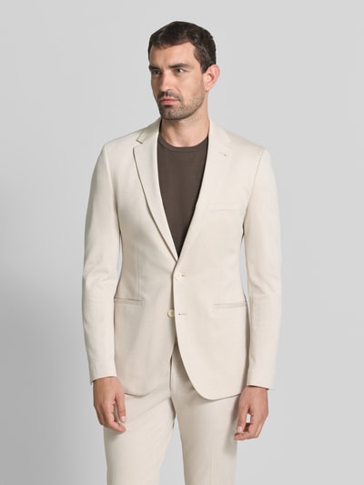 Männermodel trägt Slim Fit 2-Knopf-Sakko mit Paspeltaschen von MCNEAL in Beige, glatte Textur, Reverskragen, Ganzkörperansicht von vorne. Viskose-Mix mit Stretch-Anteil, passende Hose, schlichte Farbgestaltung.