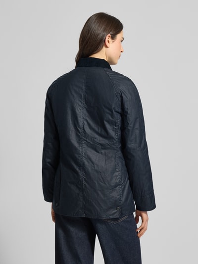 Männermodel trägt Wachsjacke aus reiner Baumwolle von Barbour, krój regular fit, umlegekragen, wasserdicht, feine webstruktur, Ganzkörperansicht Rückansicht.