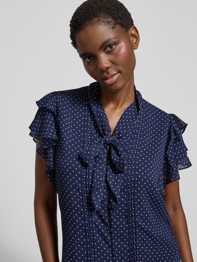 Frauenmodel trägt Regular Fit Schluppenbluse mit Volants Modell 'PRUGAN' von Lauren Ralph Lauren in Dunkelblau mit weißen Punkten, Nahaufnahme Oberkörper.