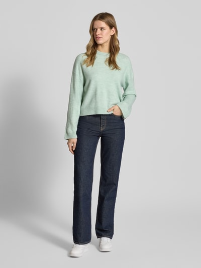 Frauenmodel trägt Relaxed Fit Strickpullover mit Crew Neck Modell 'SIMONI' von Only in Melange-Optik, Rundhals, hellgrün, Ganzkörperansicht von vorne.