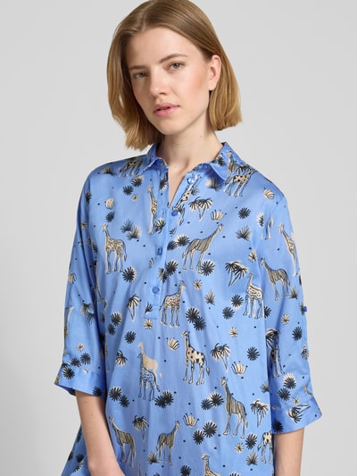 Frauenmodel trägt Relaxed Fit Kleid mit Allover-Motiv-Print von Smith and Soul aus Reiner Baumwolle in Blau mit Umlegekragen, Halbarm und Knopfleiste, Nahaufnahme Oberkörper.