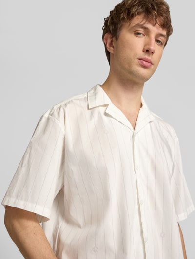 Männermodel trägt Relaxed Fit Freizeithemd aus reiner Baumwolle Modell 'Eligino' von HUGO in Optik: Unifarben, Muster: Gestreift, Resort Hemdkragen, Knopfleiste einreihig, Ärmelform: Kurzarm, Popeline, Rückenpasse, Nahaufnahme Oberkörper.