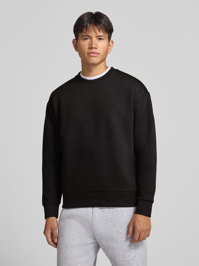 Männermodel trägt Regular Fit Sweatshirt mit Baumwoll-Anteil von JACK & JONES in Schwarz, schlichtes Design, Nahaufnahme Oberkörper. Material-Mix, Rundhalsausschnitt, elastische Abschlüsse, langärmlig, Rückenlänge bei Größe M 65 cm, Ärmellänge 59 cm.