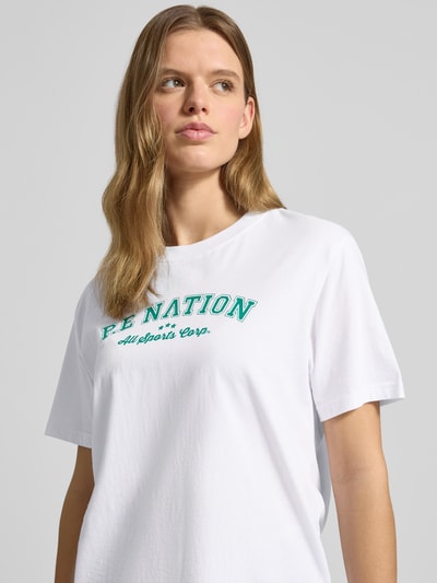 Frauenmodel trägt T-Shirt mit Logo-Print und Rundhalsausschnitt von P.E Nation aus Reine Baumwolle im Relaxed-Fit, Vorderansicht Nahaufnahme Oberkörper. Rückenlänge bei Größe S: 64 cm.