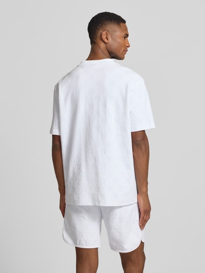 Männermodel trägt Regular Fit T-Shirt aus Baumwoll-Mix Modell 'TS_MEMBER' von BOSS Green in Weiß mit feinem Strukturmuster, Ganzkörperansicht Rückansicht.