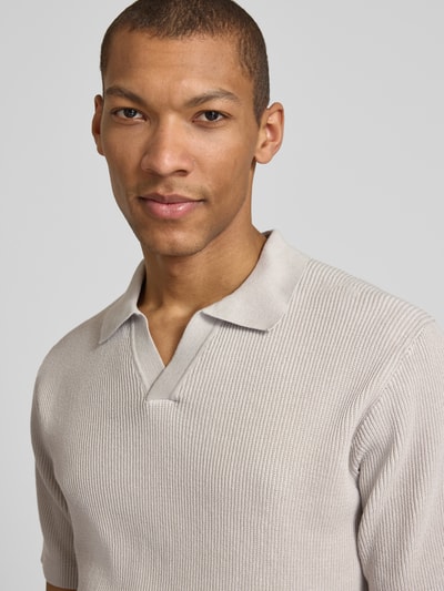 Männermodel trägt Regular Fit Poloshirt aus reiner Baumwolle Modell 'ARAVOLO' von BOSS Orange, Rippstrick, Label Patch, Nahaufnahme Oberkörper.