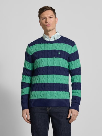 Männermodel trägt Regular Fit Strickpullover aus reiner Baumwolle von Polo Ralph Lauren in Two-Tone, Zopfmuster, Optik: Unifarben, Strickoptik, Logo-Detail, Rundhals, Langarm, Ärmel- und Rumpfabschluss gerippt, Ganzkörperansicht von vorne.