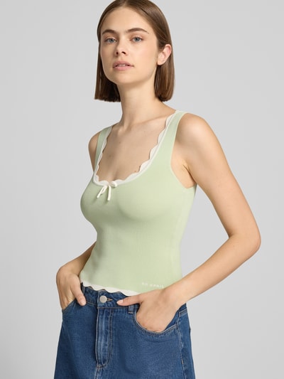 Frauenmodel trägt Crop Top mit Wellensaum Modell 'Anele' von OH APRIL in Hellgrün, Viskose-Mix, mit Schnürung, Nahaufnahme Oberkörper.