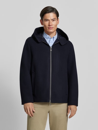 Męski model nosi Regular Fit Jacke aus Schurwoll-Mix od Armani Exchange, ciemnogranatowa, wpuszczane kieszenie, kaptur z tunelem, zamek błyskawiczny dwustronny, długość tyłu w rozmiarze M: 74 cm, szerokość ramion w rozmiarze M: 50 cm, szerokość klatki piersiowej w rozmiarze M: 61 cm, długość rękawów w rozmiarze M: 66 cm, widok całej sylwetki z przodu.