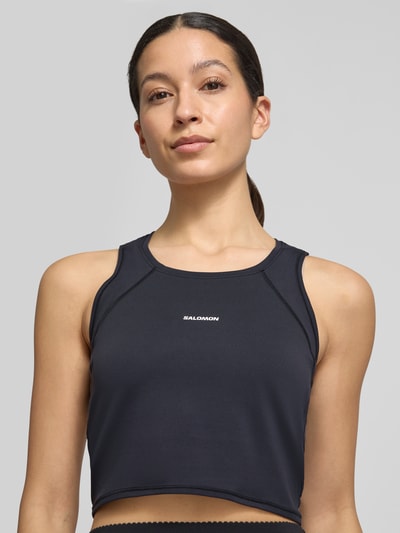Frauenmodel trägt Cropped Tanktop mit Logo von Salomon aus Material-Mix mit Stretch-Anteil, Rundhalsausschnitt, Nahaufnahme Oberkörper.