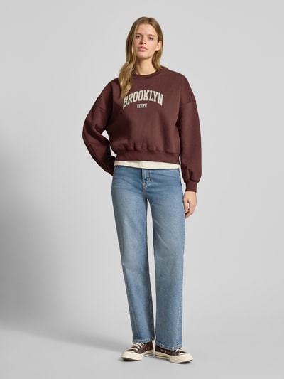 Frauenmodel trägt Sweatshirt mit Label-Print und Rundhalsausschnitt von Review im Baumwoll-Mix, Relaxed-Fit, Ganzkörperansicht von vorne.