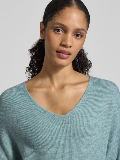 Frauenmodel trägt Regular Fit Pullover mit V-Ausschnitt Modell 'CREWLEFILE' von Vero Moda, Optik: Unifarben, Rippstrick, Nahaufnahme Oberkörper.