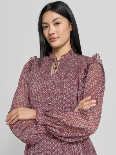 Frauenmodel trägt Knielanges Kleid mit Bindegürtel von Christian Berg Woman Selection in A-Linie mit Smok-Details, Allover-Look, Rüschen und Bindegürtel, transparentes Muster in Violetttönen, Nahaufnahme Oberkörper.