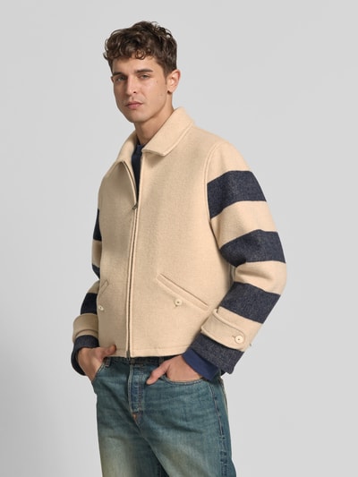 Männermodel trägt blouson uit zuiver viscose van KENZO in recht pasvorm, steekzakken, contraststrepen, tweewegritssluiting, ruglengte maat M 64 cm, schouderbreedte maat M 46 cm, mouwlengte maat M 65 cm, beige en donkerblauw, ganzkörperansicht van voren