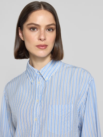 Frauenmodel trägt Relaxed Fit Bluse aus Lyocell mit Button-Down-Kragen von Gant, blauer Streifen, Brusttasche, Nahaufnahme Oberkörper. Rückenlänge bei Größe 36: 73 cm, Ärmellänge bei Größe 36: 59 cm.
