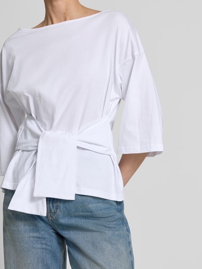 Frauenmodel trägt Shirt mit U-Boot-Ausschnitt Modell 'Dajana' von GUIDO MARIA KRETSCHMER WOMAN, reine Baumwolle, taillierter Schnitt, 3/4-Arm, Raffung, Rückseite 56 cm bei Größe 36, Weiß, glatte Textur, simple Formen, Nahaufnahme Oberkörper.