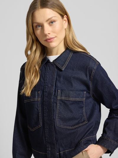 Kobiece model prezentuje Regular Fit Jeansjacke aus Baumwoll-Mix von Tom Tailor, ciemny denim, kieszenie na piersi, wykładany kołnierz, mieszanka bawełny, haft motyw, splot twill, listwa z zatrzaskami, długi rękaw, zakończenie rękawów mankietami, pas na plecach, półzbliżenie przód.