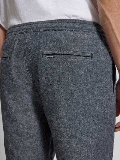 Männermodel trägt Regular Fit Bermudas aus Leinen-Baumwoll-Mix Modell 'STILLWATER' von Barbour in grauer Melange-Twill-Optik, Nahaufnahme Rückansicht.