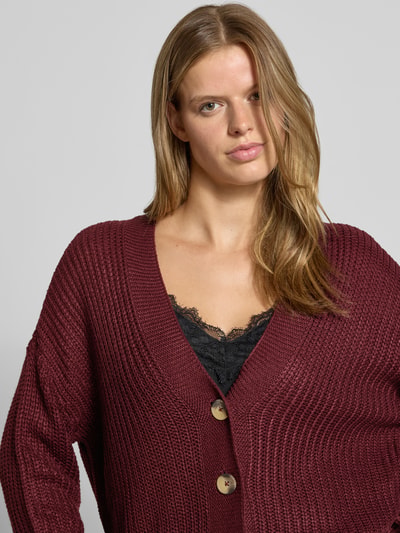 Vrouwenmodel draagt boxy fit gebreid jack met v-hals model 'CAROL' van ONLY in bordeauxrood, grove textuur, Dames, Nahaufnahme Oberkörper.