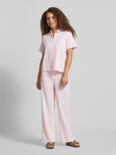 Frauenmodel trägt Regular Fit Hemdbluse aus reiner Baumwolle Modell 'TINNA' von Pieces mit Allover-Muster in Rosa und Weiß, Ganzkörperansicht von vorne.