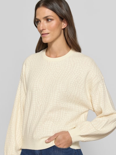 Vrouwenmodel draagt Regular Fit Pullover aus Viskose-Mix model 'NANCY' van VERO MODA voor Dames, crème met structuurpatroon, close-up bovenlichaam.