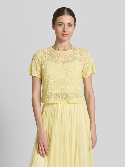 Frauenmodel trägt Cropped T-Shirt mit Pailletten von LACE & BEADS aus Mesh in Gelb mit Rundhalsausschnitt, Rückenlänge 41 cm, Ganzkörperansicht von vorne.
