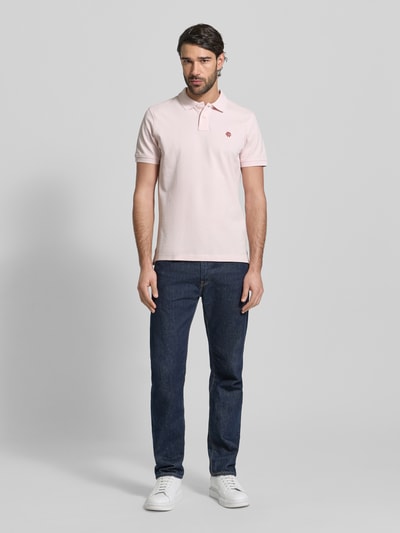 Männermodel trägt Slim Fit Poloshirt mit Logo-Stitching von MCNEAL in Hellrosa, reine Baumwolle, Polokragen, Ganzkörperansicht von vorne.