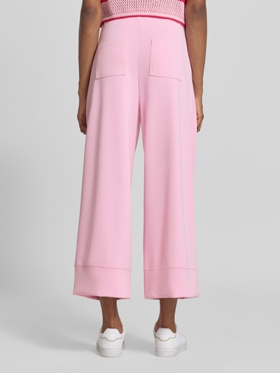 Frauenmodel trägt Wide Leg Sweatpants aus Modal-Mix von Rich & Royal in Rosa mit ausgestelltem Bein, Bundfalten und Gesäßtaschen, Ganzkörperansicht Rückansicht.