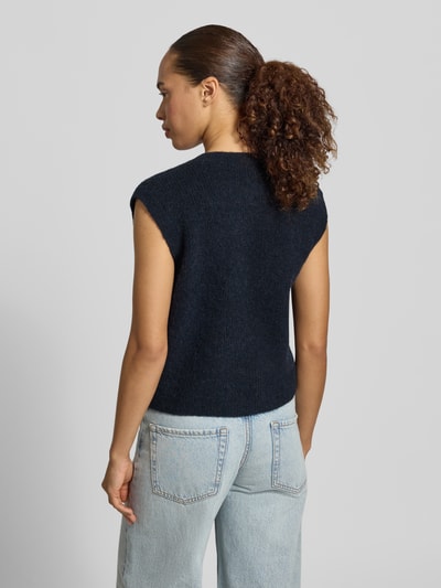 Frauenmodel trägt dunkelblaue Regular Fit Strickweste aus Woll-Mix Modell 'LULU' von Selected Femme, kombiniert mit Jeans, Ganzkörperansicht Rückansicht. Damen Strickweste von Selected Femme.