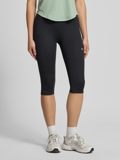 Frauenmodel trägt Tights mit elastischem Bund und Logo von NIKE TRAINING in Schwarz, Material-Mix mit Stretch-Anteil, körpernahe Passform, Nahaufnahme Unterkörper.