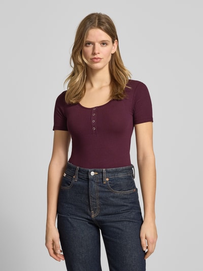 Modelka nosi damski t-shirt Slim Fit T-Shirt aus Baumwoll-Mix Modell 'KITTE' von Pieces, efekt: jednolity kolor, krój slim fit, dekolt w łódkę, dekolt henley, krótki rękaw, prążkowana faktura, mieszanka bawełny, widok na całą sylwetkę z przodu.