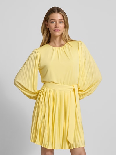 Modelka kobieca nosi żółtą sukienkę mini z plisowanymi rękawami i spódnicą, pasek, okrągły dekolt, Cocktailkleid mit Plisseefalten Modell 'Celina' od GUIDO MARIA KRETSCHMER WOMAN, krój slim fit, widok całej sylwetki od przodu