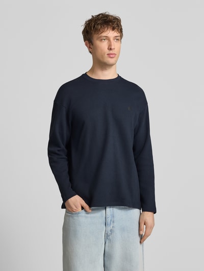 Männermodel trägt Longsleeve aus Baumwolle Modell 'FILLIP' von Blend in Dunkelblau, Gerader-Schnitt, Rundhalsausschnitt, Label-Detail, Nahaufnahme Oberkörper. Rückenlänge bei Größe M: 70 cm.