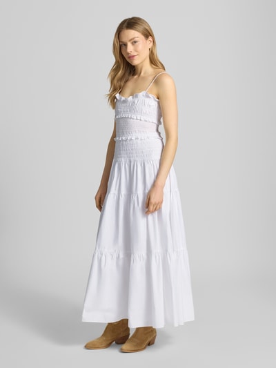 Frauenmodel trägt Midikleid mit Rüschen und Volantsaum von MICHAEL Michael Kors in Weiß, tailliert mit Smok-Details, Baumwolle, Ganzkörperansicht von vorne.