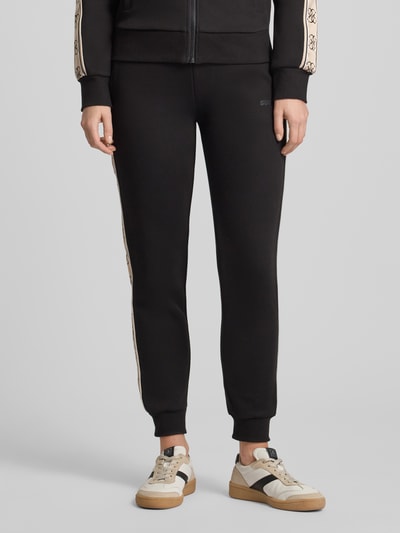 Frauenmodel trägt schwarze Sweatpants mit elastischem Bund Modell 'BRITNEY' von Guess Activewear aus Baumwoll-Mix, Nahaufnahme Unterkörper.