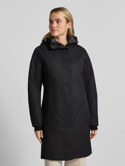 Modelka kobieca nosi czarny Parka mit Kapuze und Eingrifftaschen Modell 'GW66' od G.I.G.A. DX, krój regular fit, klasyczna struktura, gładka tekstura, długi rękaw, widoczne kieszenie, długość do kolan, widok całej sylwetki z przodu. Długość pleców w rozmiarze 36: 94 cm, szerokość ramion w rozmiarze 36: 42 cm, szerokość klatki piersiowej w rozmiarze 36: 47 cm, długość rękawa w rozmiarze 36: 65 cm.