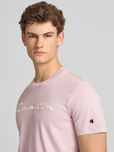 Männermodel trägt T-Shirt mit Label-Stitching mit Rundhalsausschnitt von CHAMPION in Rosa, Reine Baumwolle, Regular-Fit, Nahaufnahme Oberkörper.